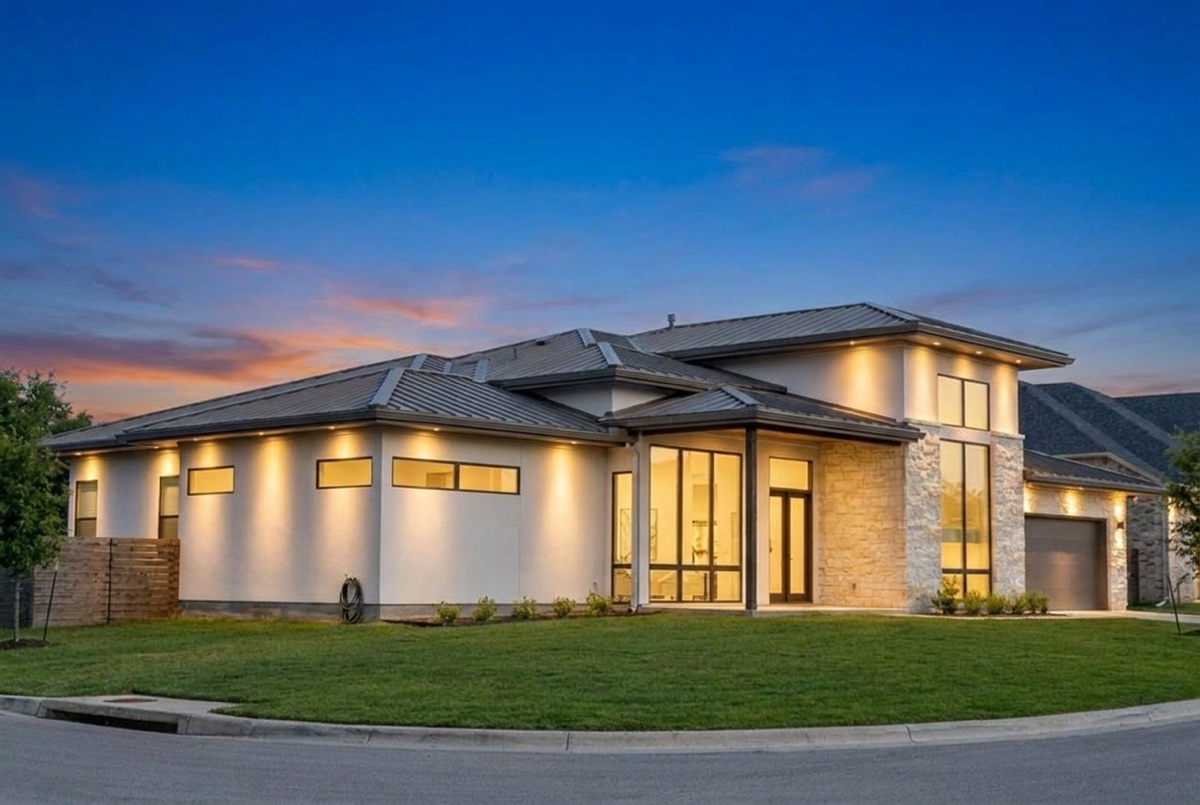 The same Austin home at dusk, eave-mounted permanent LED washing warm light down the walls