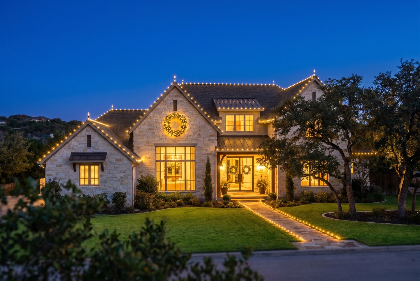 Austin limestone two-story with warm-white roofline and a wreath on the peak