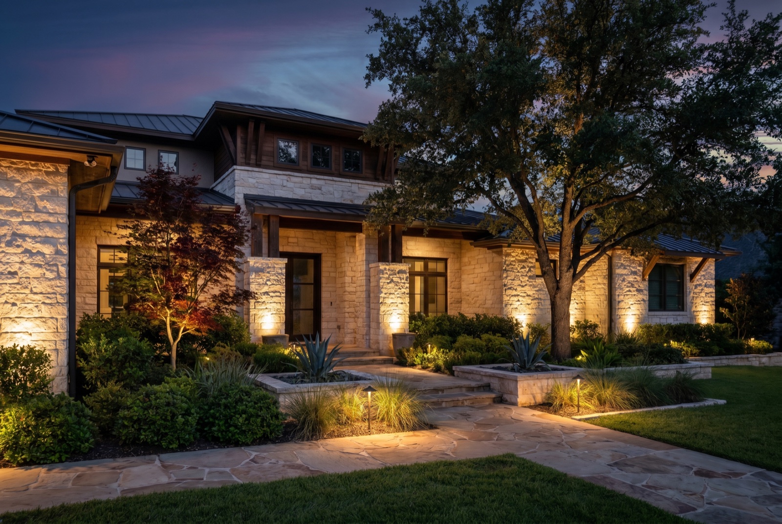 Austin home with warm landscape uplighting and lit path